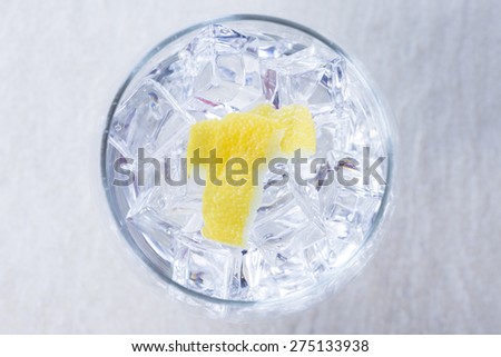 top view of a gin tonic balloon glass with lemon peels on it on a flavoring process on a gin tonic preparation session - focus on the lemon peel
