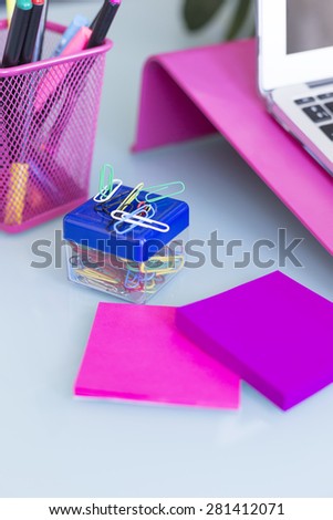 paperclip box with colored post it on a working desk - focus on the yellow paperclip