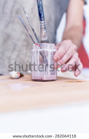 closeup of a hand of a painter cleaning the paintbrushes at his painting studio - focus on the paintbrush