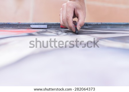 top view of the hand of a painter painting with chalk on canvas - focus on the index finger