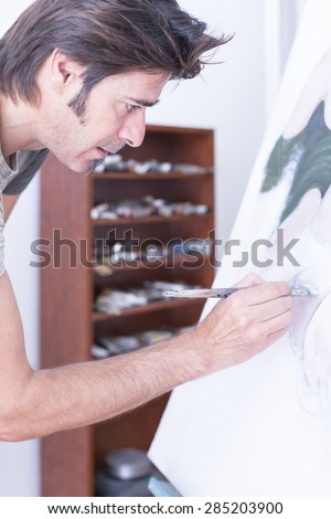 young man painting on canvas at his painting studio - focus on the eye