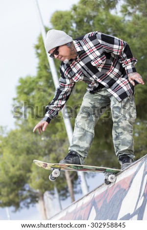 old man skater is ready to jump with a skateboard on a skating park - focus on the face