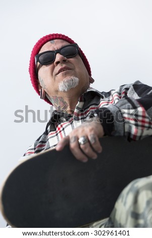 bottom view of an old man skater holding his skateboard at a skate park - focus on the face