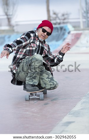 old man skater is enjoying skating with his skateboard on a skating park - focus on the face