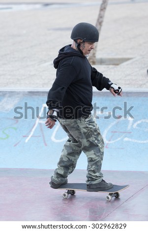 old man skater skating with a skateboard on a skating park - focus on the face