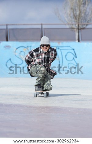 old man skater is skating crouched with his skateboard on the skating park - focus on the face