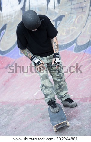 concentrated old man skater ready to skate with his skateboard on a skate park - focus on the face