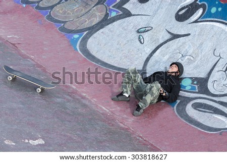 old man skater lying down on the floor is resting on a skating park - focus on the face