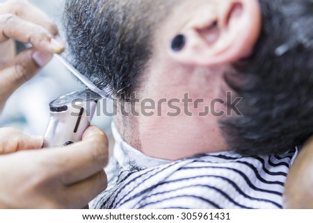 detail of a beard is being shaved with a hair clipper - focus on the comb