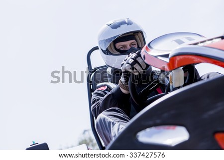view from below of a concentrated gokart pilot on the starting line before starting a race in an outdoor go karting circuit - focus on the right eye