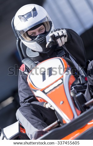 closeup of a karting driver pointing with the finger on a challenging sign before starting a race in an outdoor go karting circuit - focus on the face