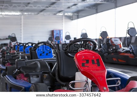 closeup of a gokart parked at the karting car park full of go-karts ready for start - focus on the front