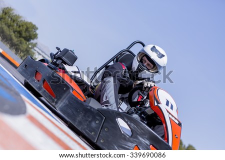 young man go-kart racer is racing a race in an outdoor go karting circuit - focus on the left eye