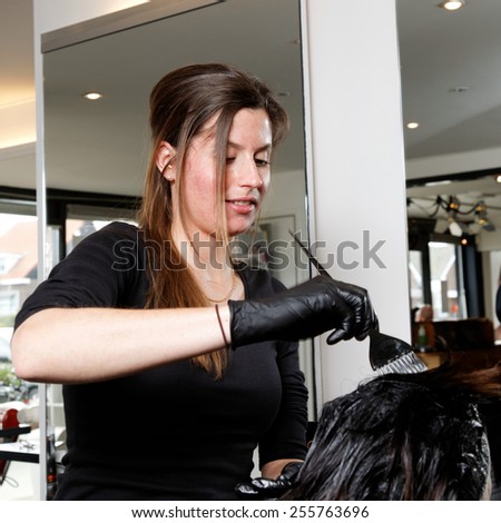 hairdresser in a salon colors the hair of a customer