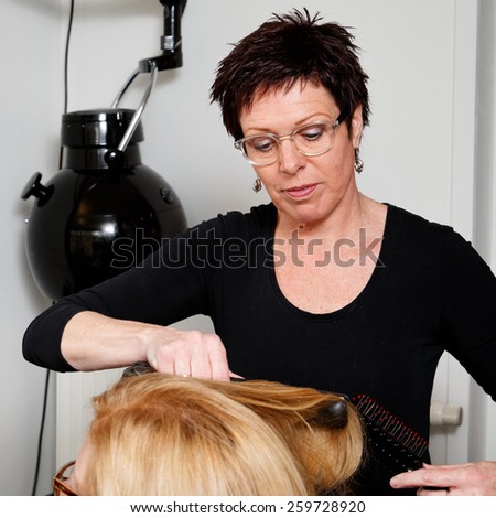 hairdresser uses brush to model hair of a customer