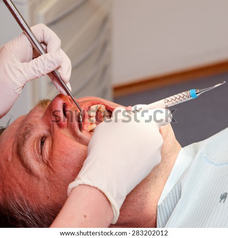 man is getting his teeth checked and cleaned at the dentist\'s office