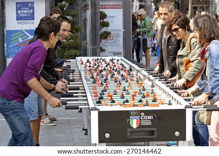 MILAN , ITALY - 10 April 2015 : group of people playing table football in the public square. this big table is insalled to favor the aggregation of unknown people of various ethnic groups