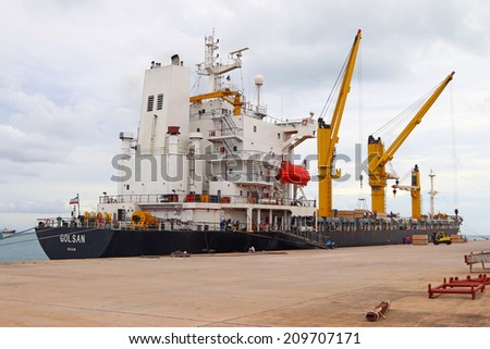 PHUKET, THAILAND - AUGUST 05 2014: Cargo ship working with crane at side Port of Phuket on August 05, 2014 in Phuket, Thailand.