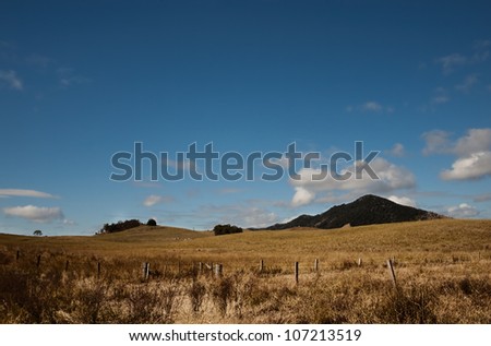 Australian dry winter pasture treeless landscape with clouds building in blue sky