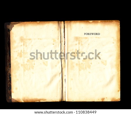 Old tattered vintage book damaged torn open aged  blank pages with faded foreword over black background