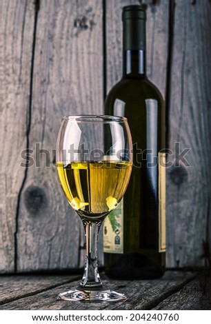 bottle of white wine and wineglass on old wood background vintage photo