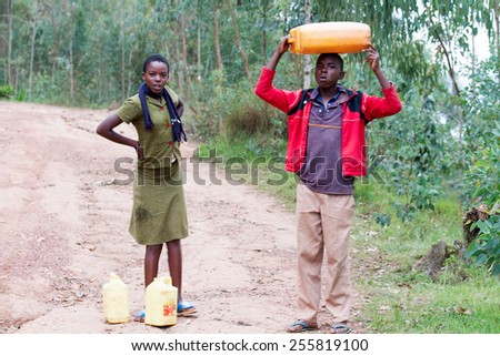 RUHENGERI, RWANDA-NOVEMBER 15, 2013: unidentified children brings a cans of potable water in Ruhengeri, Rwanda, November 15, 2013