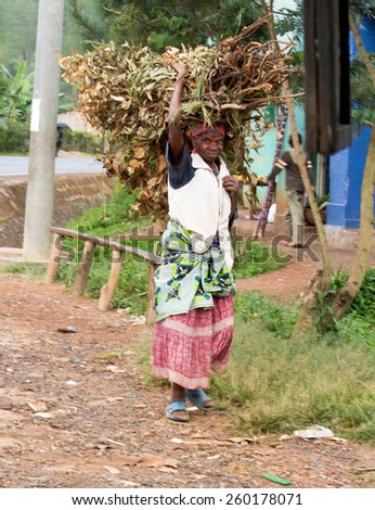 RUHENGERI, RWANDA-NOVEMBER 3, 2013: unidentified woman carries the woods above the head in Ruhengeri, Rwanda, November 3, 2013