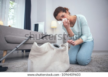 Safety violation. Adolescent woman being prone to dust allergies suffering from consequences of not wearing any personal protective equipment while cleaning dirty carpet