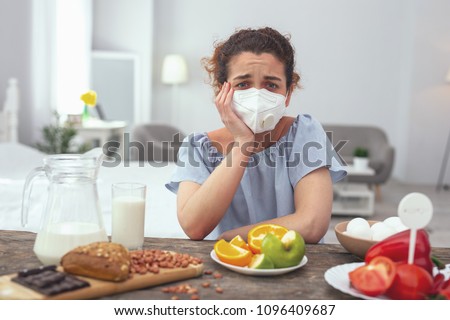 Impossible choice. Young upset looking woman feeling unfortunate while suffering from multiple food allergies causing her discomfort and limiting her food choices