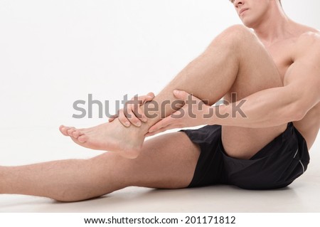 Young  sportsman, fitness muscle model guy feeling pain in his ankle isolated on white. Concept of sport, pain