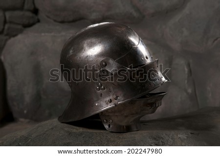 Closeup of knight armor helmet on the dark stone wall background