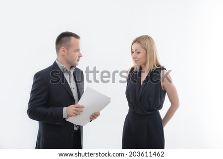 Handsome boss in suit holding blank paper looking precisely at embarrassed young attractive woman employee, isolated on white