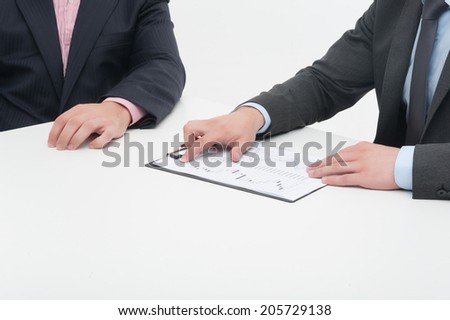 Two business people in elegant suits working in team together with documents, holding clipboard with papers isolated on white background