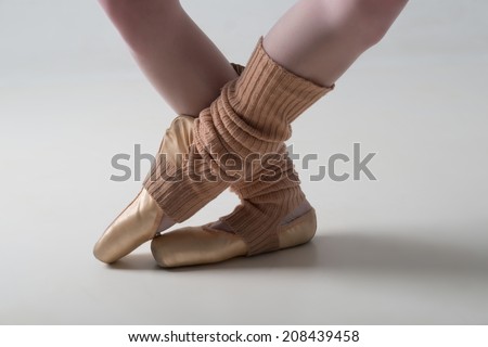 Closeup portrait of a dancer, legs in ballet shoes and long socks dancing in pointe isolated on white background