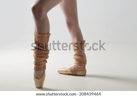 Closeup portrait of a dancer, legs in ballet shoes and long socks dancing in pointe isolated on white background