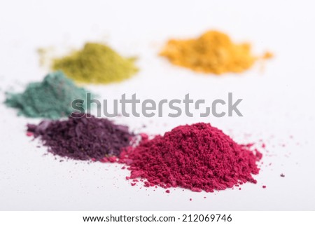 Close-up low angle view of  heaps crashed in small pieces eye shadow in pink, blue, yellow, green and purple colours isolated on white background