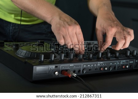 Closeup portrait of DJs hands mixing and spinning music on mixer isolated on dark background
