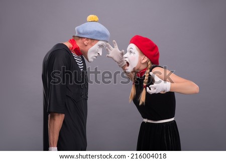 Waist-up horizontal portrait of couple of two mimes standing face to face and screaming on each other, male mime very angry isolated on grey background with copy place