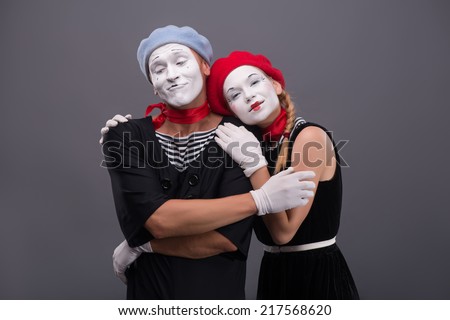 Waist-up portrait of mime couple hugging with love each other, isolated on grey background with copy place, relationships between man and woman