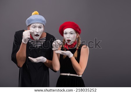 Waist-up portrait of sad mime couple pitifully crying and looking at the camera, both mimes putting their tears in their hands isolated on grey background with copy place