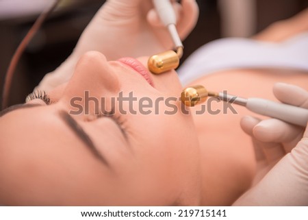 Close-up portrait of face of a young woman with fresh and clean skin lying on a table in healthy beauty spa salon getting a professional cosmetology skin care with specialized equipment