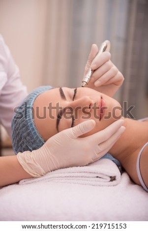 Side-view portrait of face of a young woman with fresh and clean skin lying on a table in healthy beauty spa salon getting a professional cosmetology skin care with specialized equipment
