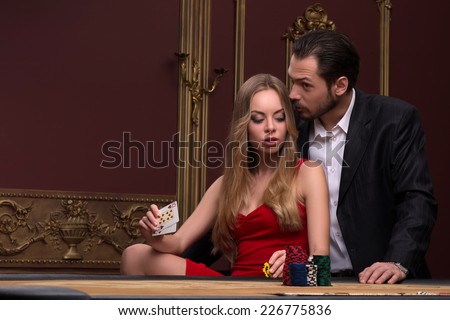 beautiful woman showing  cards  looking at and handsome  man in casino sitting at table waist up