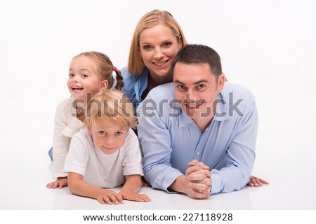 Happy family of father mother son and daughter smiling  lying on each other   looking  at camera  isolated on white background