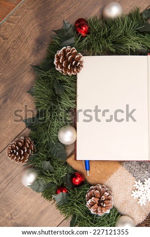 Christmas tree toys  and decoration like  wreath of fir branches and cones and clear sheet  of paper  with pen on wooden table with  top view  and  copy place