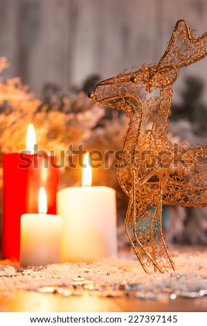 Christmas decoration   like wicker iron deer at red and white lightning candles  and fir branches  with selective focus