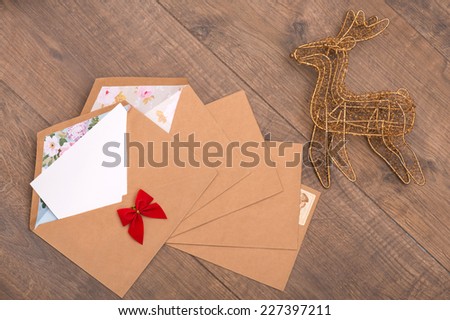 Christmas tree toys and  decoration like envelopes with red bows  with white clear sheet s of paper  and wicker  iron deer  on wooden table top view