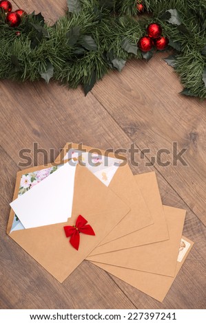 Christmas tree toys and  decoration like envelopes with red bows  with white clear sheet s of paper  and fir branch on wooden table top view  with copy place