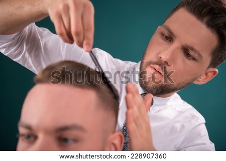 hairdresser  does   hair  with black comb of handsome satisfied  client in  professional  hairdressing salon