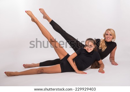 Young sport  mother and  daughter teenager lying on floor doing leg swing smiling isolated on white background